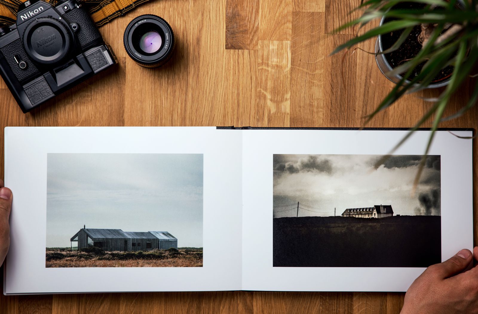 An open photo album on a wooden table with a camera and lens nearby