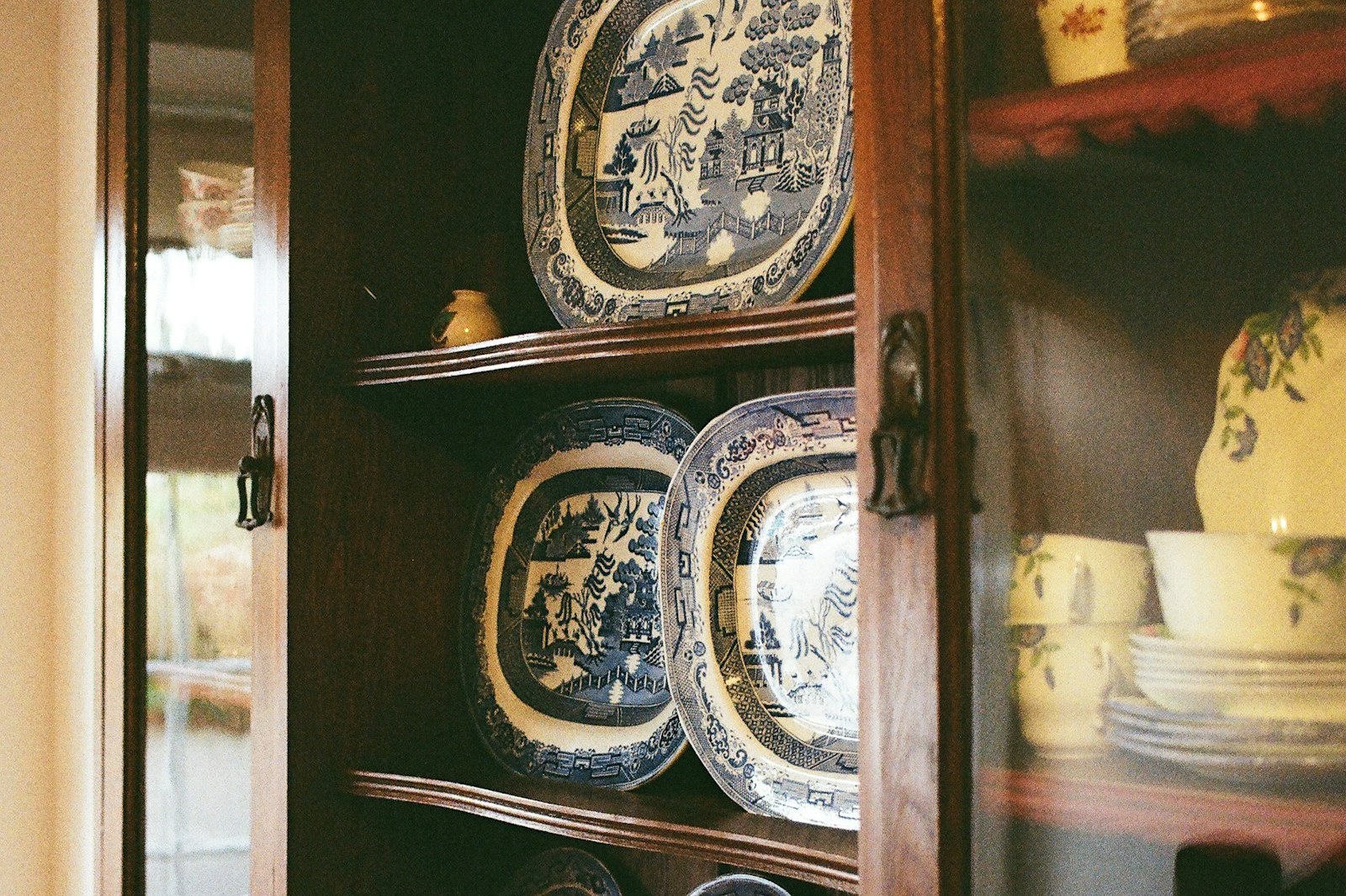 Antique blue and white china plates displayed in a wooden china cabinet