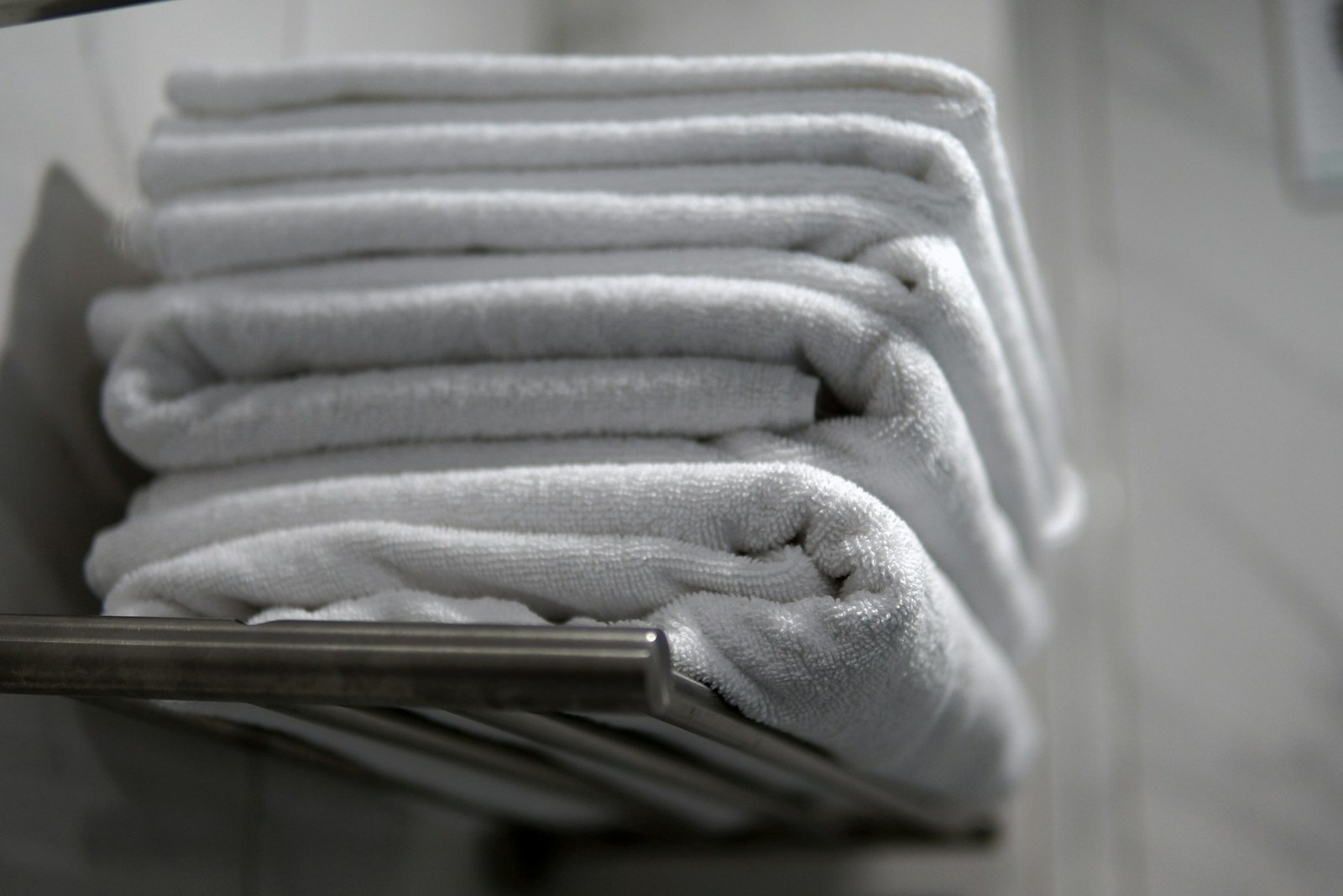 A stack of folded white towels on a brushed metal rack