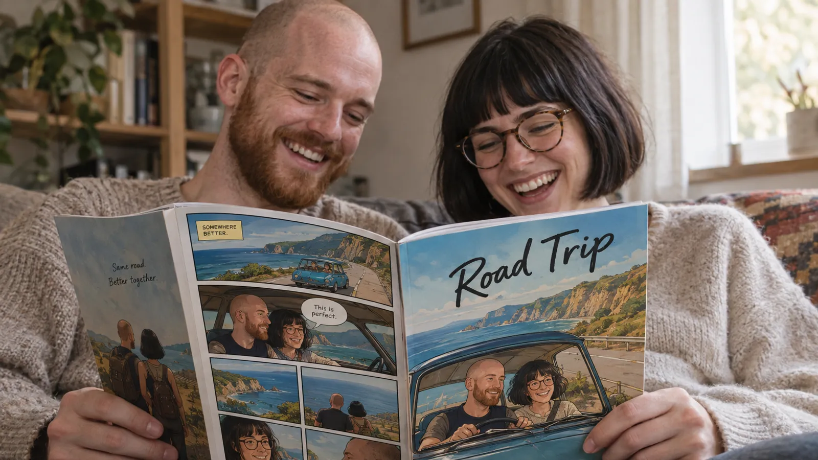 a man in his late twenties with a shaved head and a short red beard, and a woman in her late twenties with a black bob haircut and round tortoiseshell glasses, sitting side by side on a sofa in soft afternoon window light, both faces visible and laughing, holding open their printed personalized comic book titled Road Trip, its lettered panels showing the two of them drawn as comic characters in a small car on a coastal road