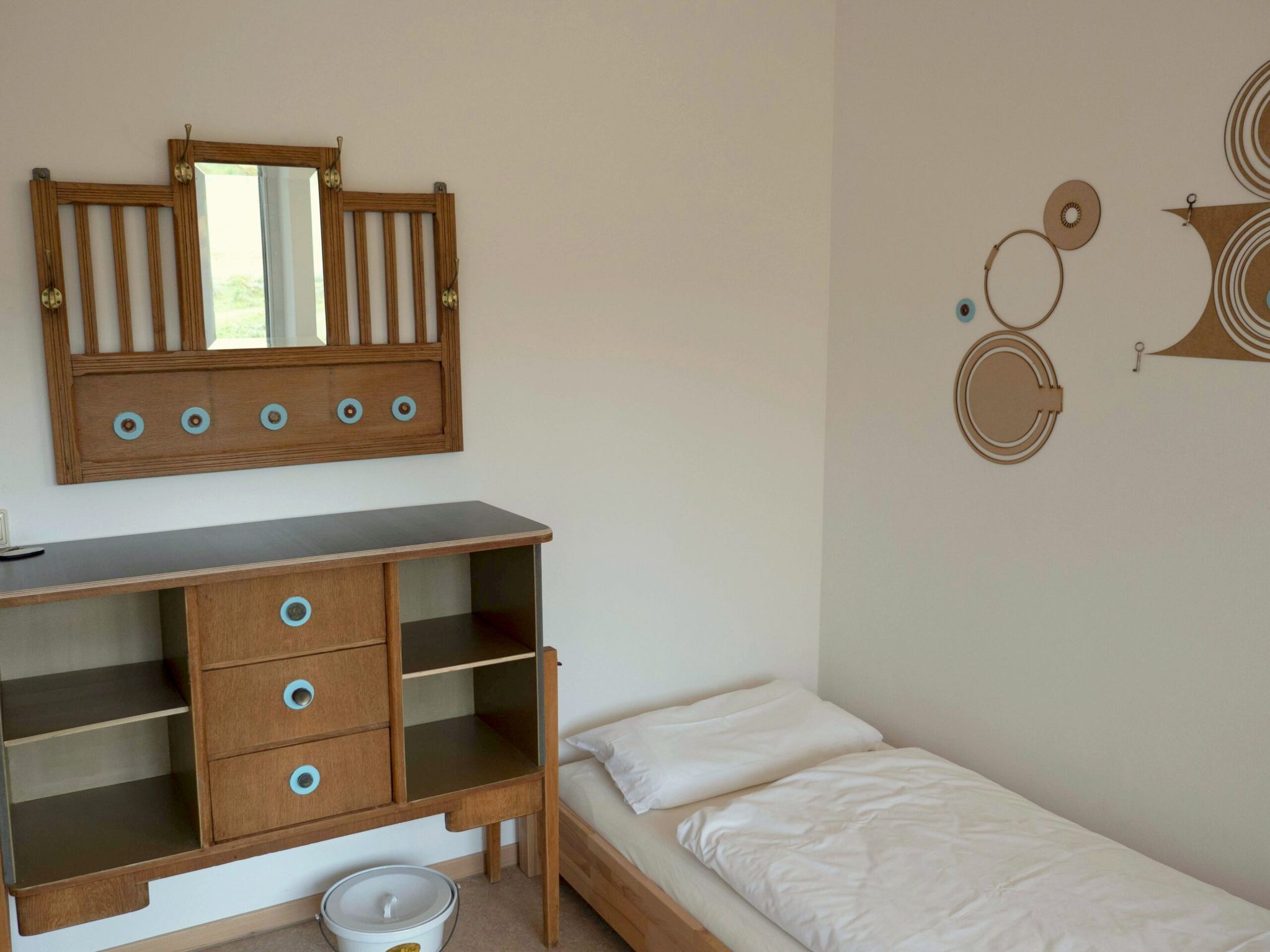 Ein Raum mit einem Bett, einem Spiegel und einem Holzschrank.