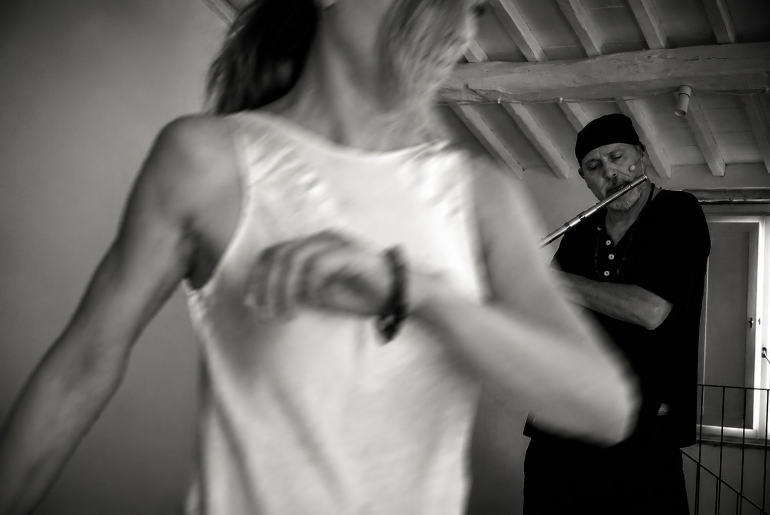 A dancer moves freely in the foreground while Alex Tarolo plays the flute in the background.