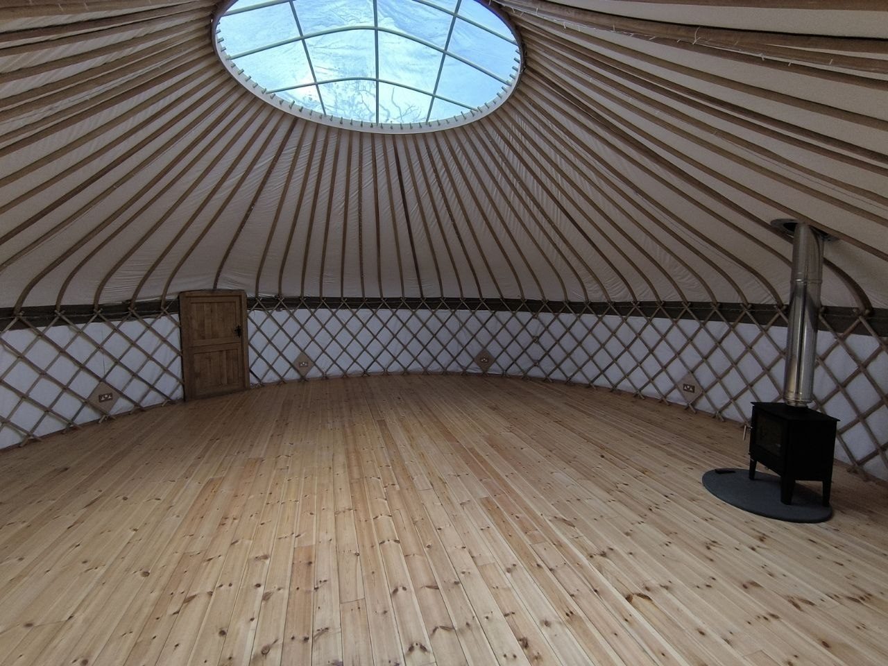 Inside the yurt at the retreat venue, with a wooden floor, a skylight and a wood burner