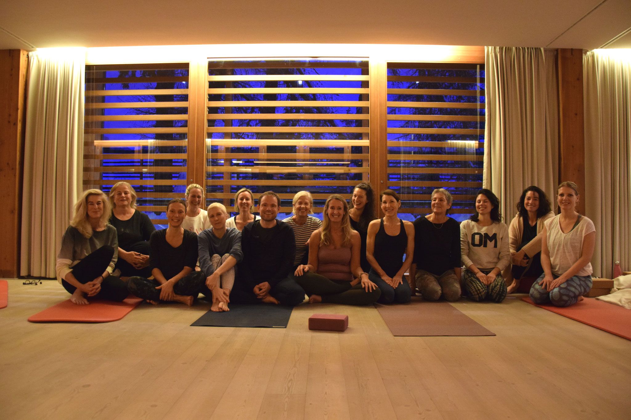 Eine Gruppe von Personen sitzt auf Yogamatten in einem Raum.