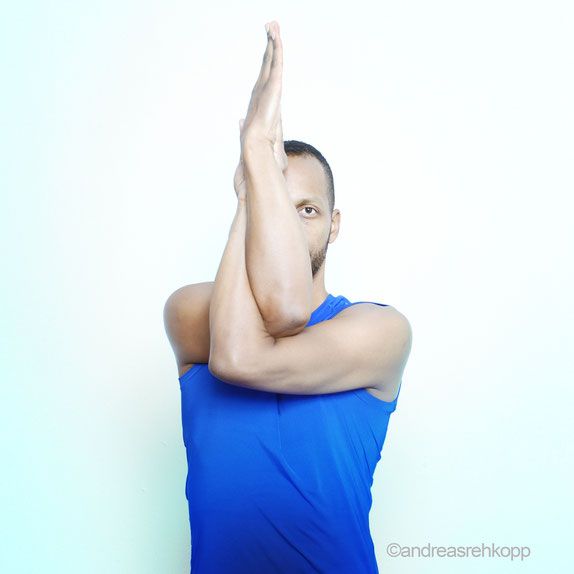Ein Mann zeigt eine Yoga-Pose mit gekreuzten Armen.