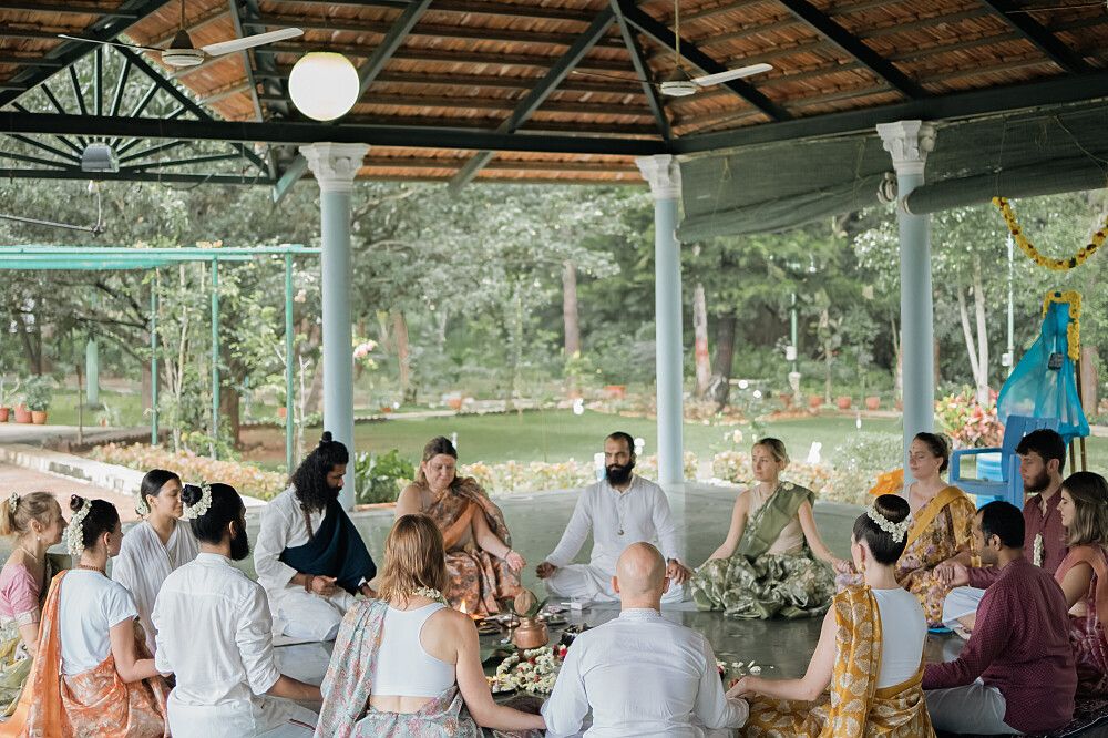 A group of people sitting in a circle, participating in a communal activity outdoors.