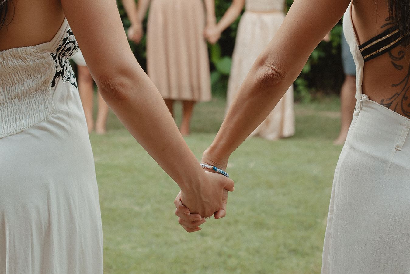 Two people holding hands in a circle with others in the background.
