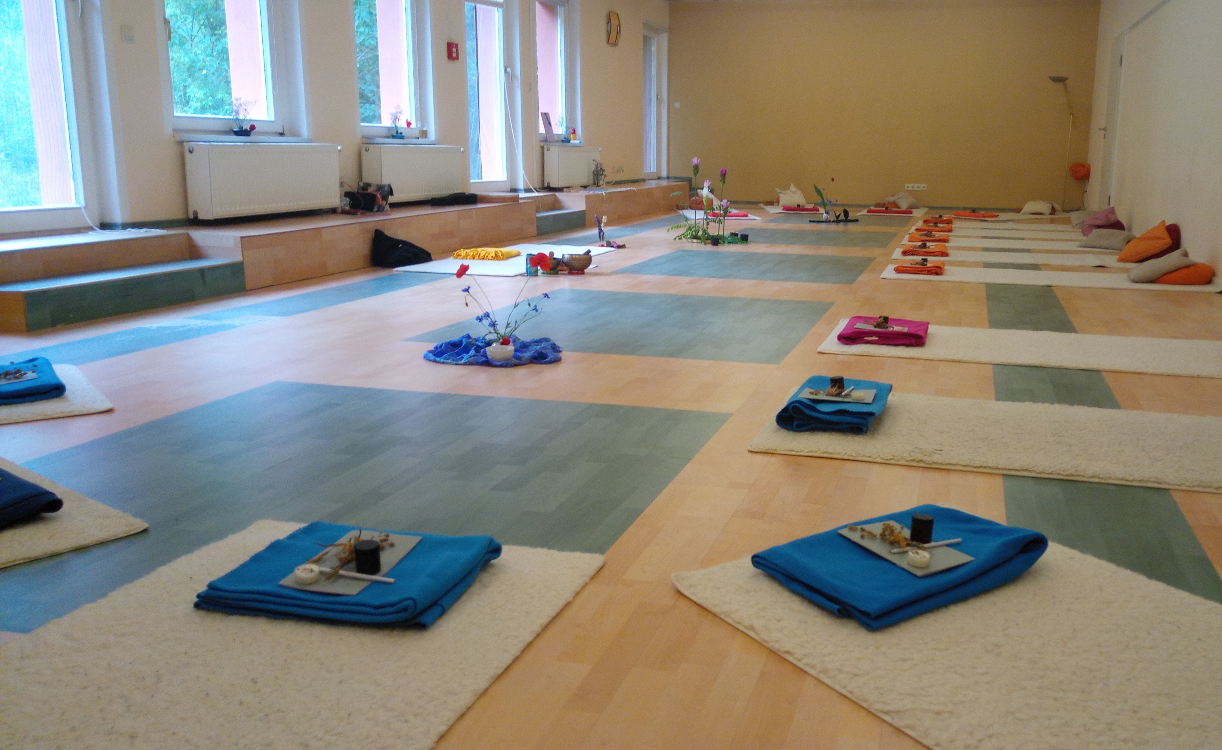 Heller Seminarraum mit vorbereiteten Yoga- und Meditationsplätzen für das Schweigeretreat.