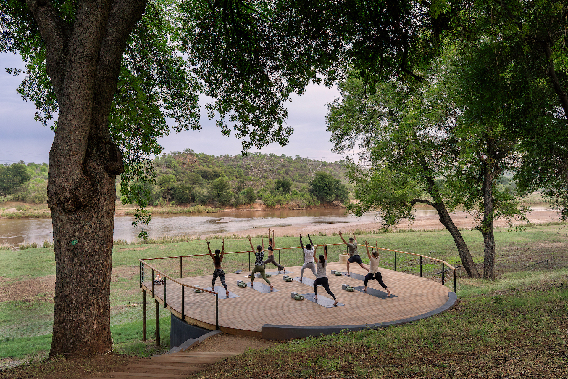 A group of woman doing yoga next to a river bed at a Safari lodge