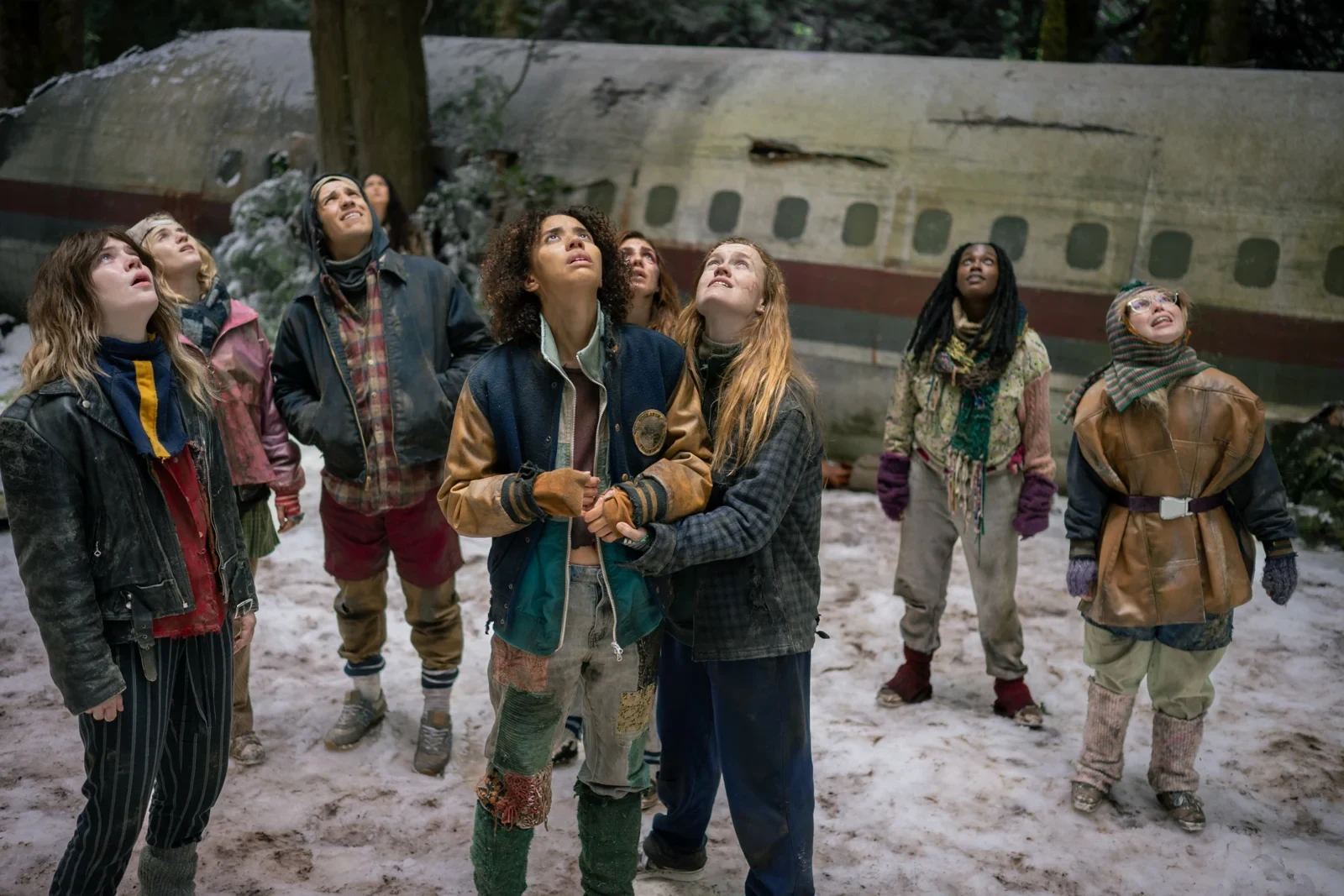 Las adolescentes del equipo miran hacia el cielo en la nieve, junto a los restos del avión