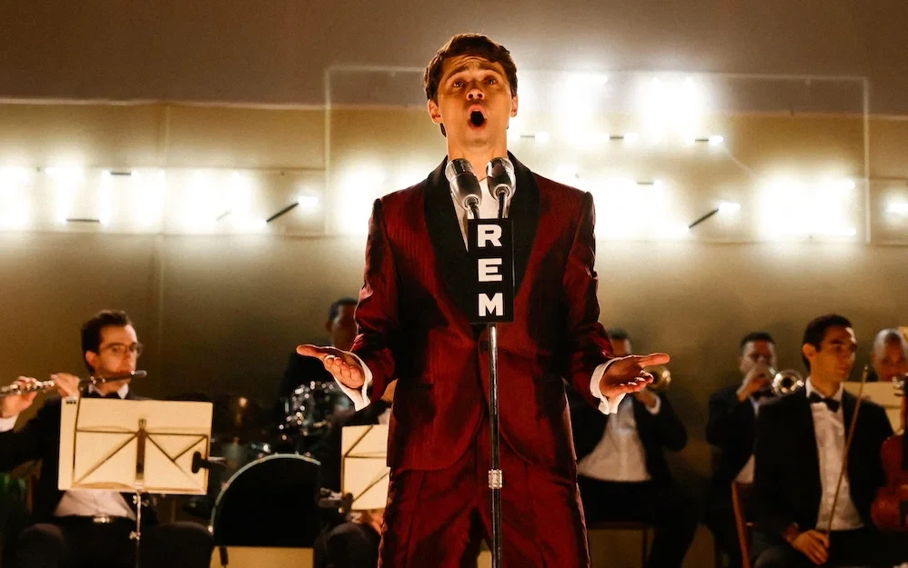 Javier Morgade como Raphael con traje rojo, cantando con orquesta en Aquel