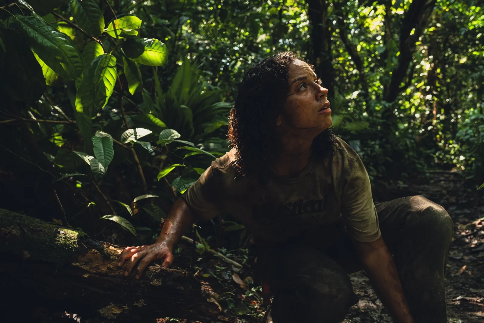 Una joven agazapada entre la vegetación de la selva