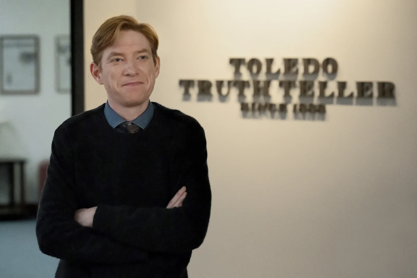 Domhnall Gleeson como Ned frente al cartel del Toledo Truth Teller