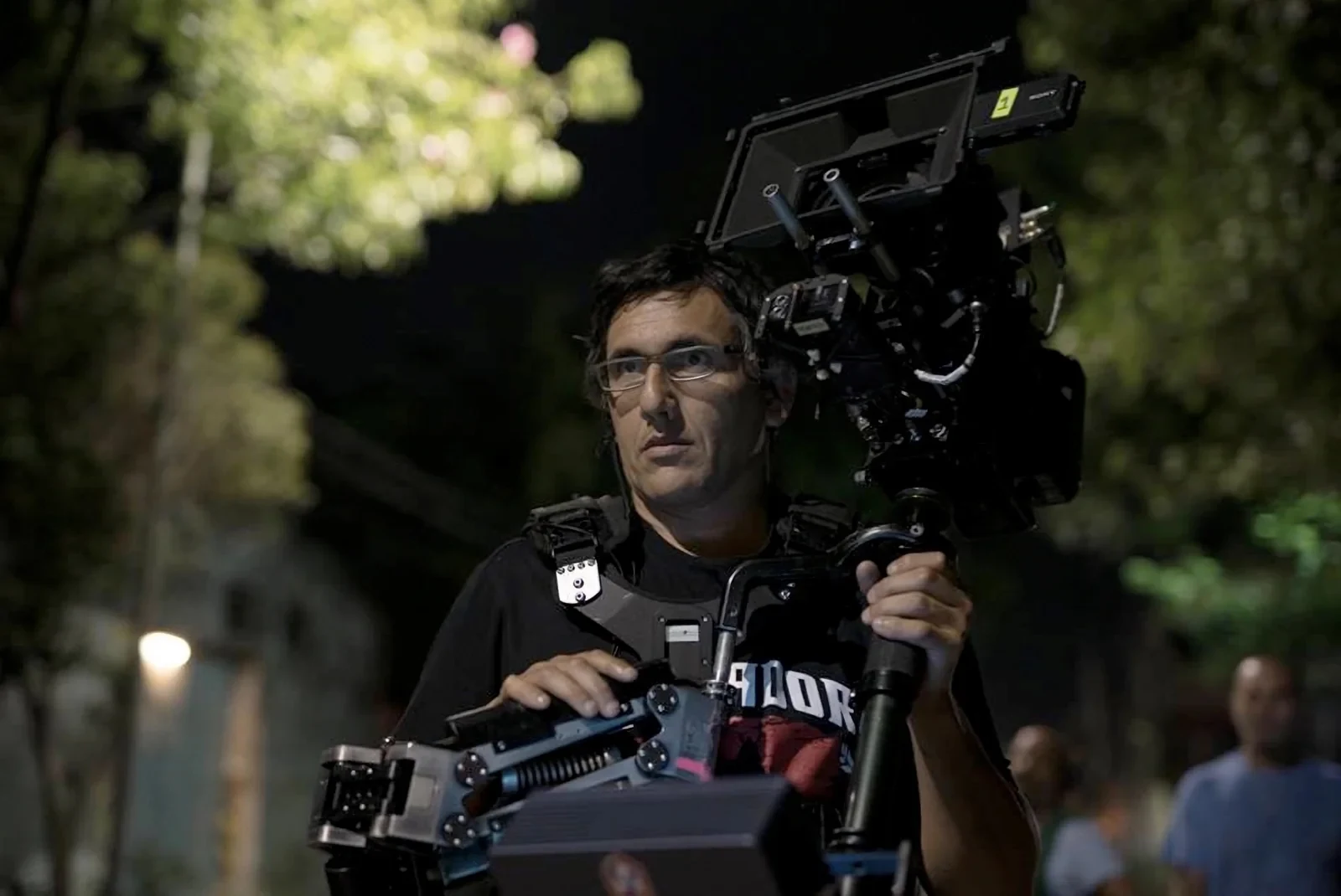 Gustavo Triviño con anteojos, operando una cámara con Steadicam de noche