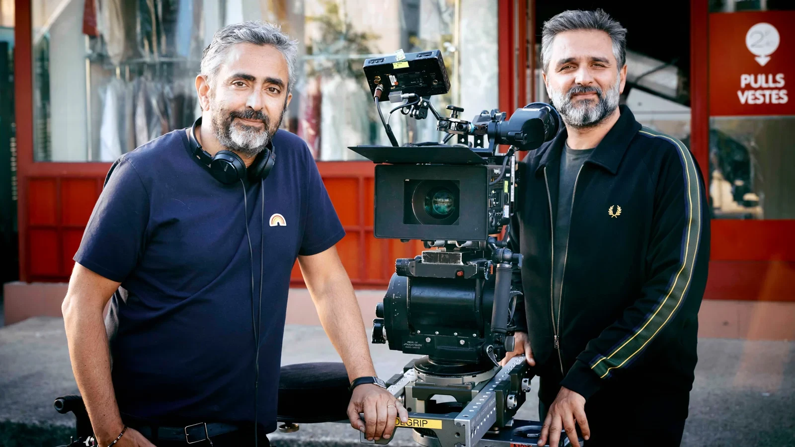 Éric Toledano y Olivier Nakache junto a una cámara de cine en una calle, durante el rodaje de Tiempos de ilusión