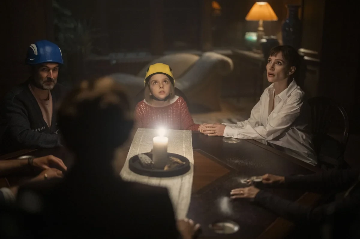 Jay Duplass, Arabella Olivia Clark y Jessica Chastain alrededor de una mesa iluminada por una vela en Madre siniestra