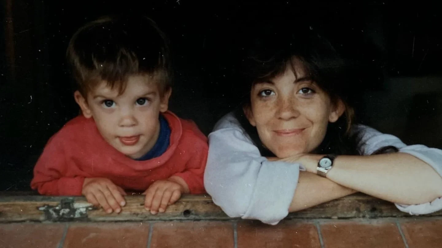 Un niño y su madre apoyados sobre una baranda de madera