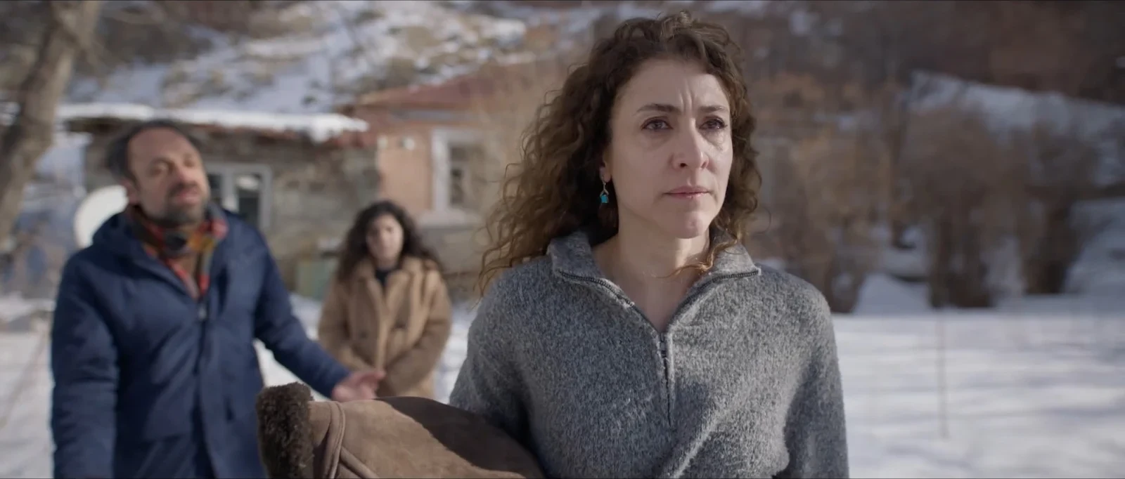 Majid Bakhtiari, Tanaz Molaei y Vishka Asayesh caminando en un pueblo nevado, en Siete días