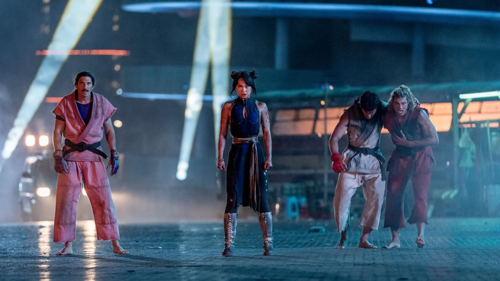 Dan, Chun-Li, Ryu y Ken, golpeados, de pie en una calle de noche en Street Fighter