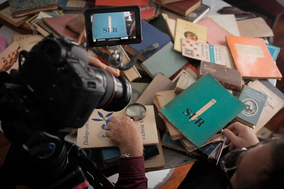 Una cámara filma libros antiguos desparramados sobre una mesa