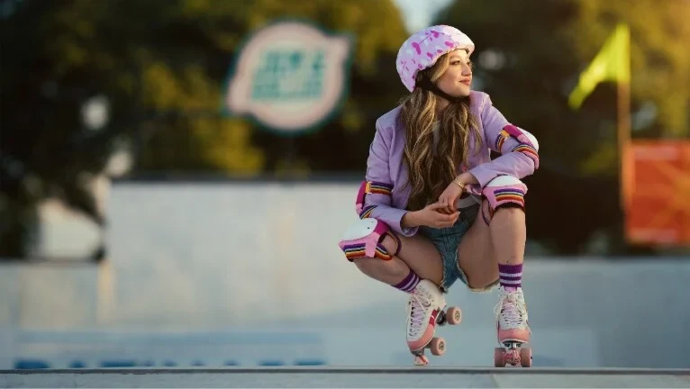 Una joven con casco y patines agachada en una pista