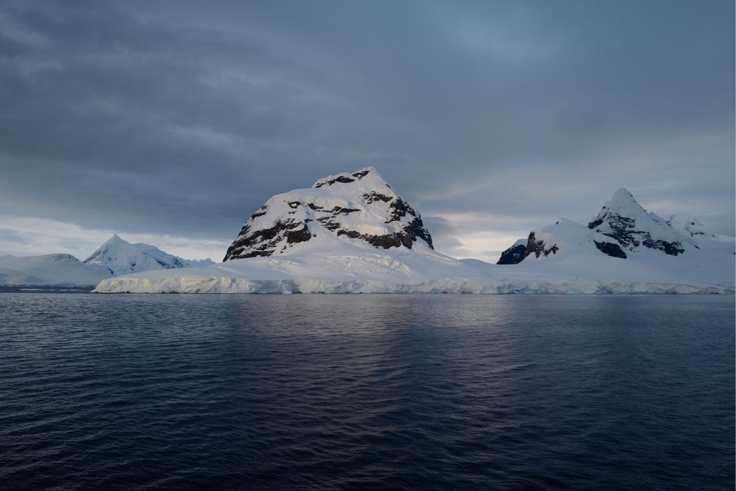 Expedition ship navigating through icebergs in Antarctica's stunning landscape.
