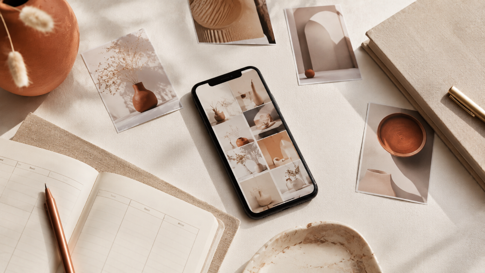 Телефон з відкритою стрічкою Instagram лежить на кремовому столі поруч з фотографіями товару.