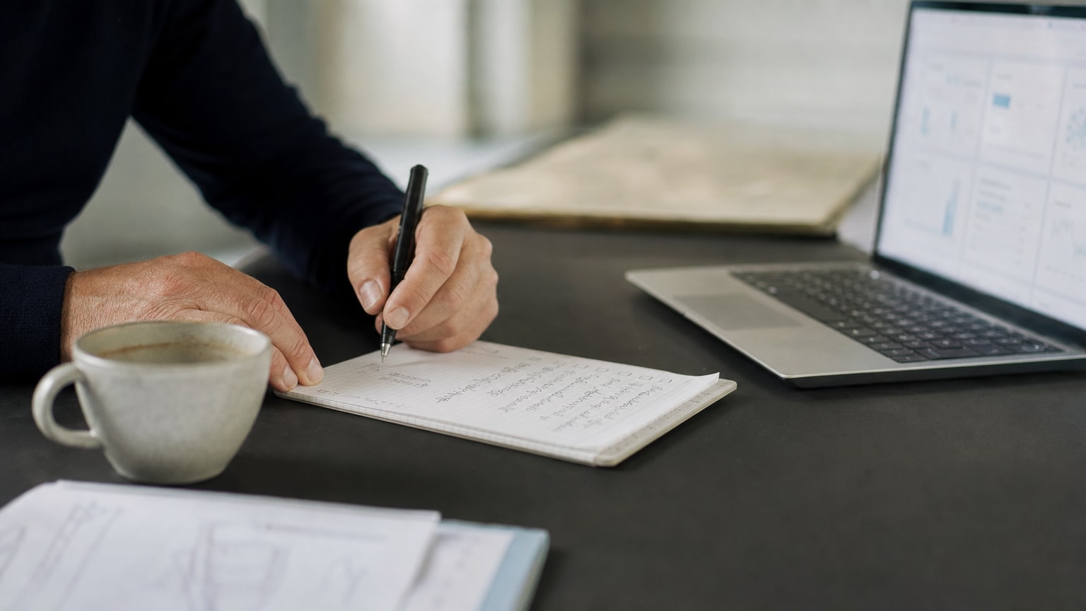 Ein aufgeräumter Schreibtisch mit einer handgeschriebenen Checkliste, einem Laptop mit Dashboard-Ansicht und einer Kaffeetasse – symbolisiert den strukturierten Auswahlprozess einer Digitalagentur durch einen KMU-Geschäftsführer.