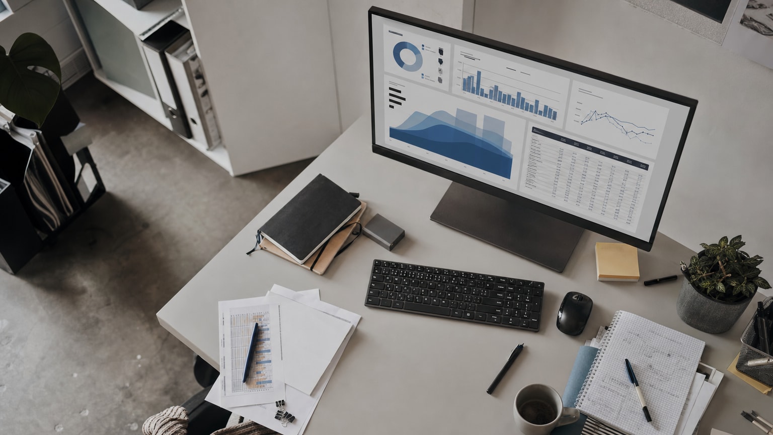 Ein übersichtliches, modernes Dashboard auf einem Bildschirm in einem kleinen Büro, das Datenvisualisierungen und Diagramme zeigt – im Hintergrund ein aufgeräumter Schreibtisch eines KMU-Geschäftsführers.
