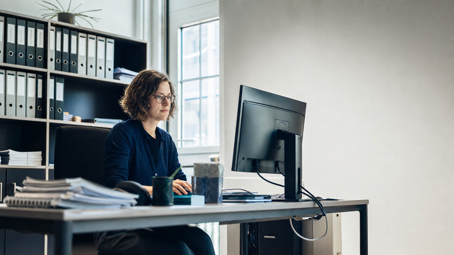Aufgeräumter Schreibtisch mit geordneten Dokumenten und einem Bildschirm, auf dem strukturierte Datenfelder zu sehen sind – symbolisch für saubere Datengrundlagen in einem KMU-Betrieb.