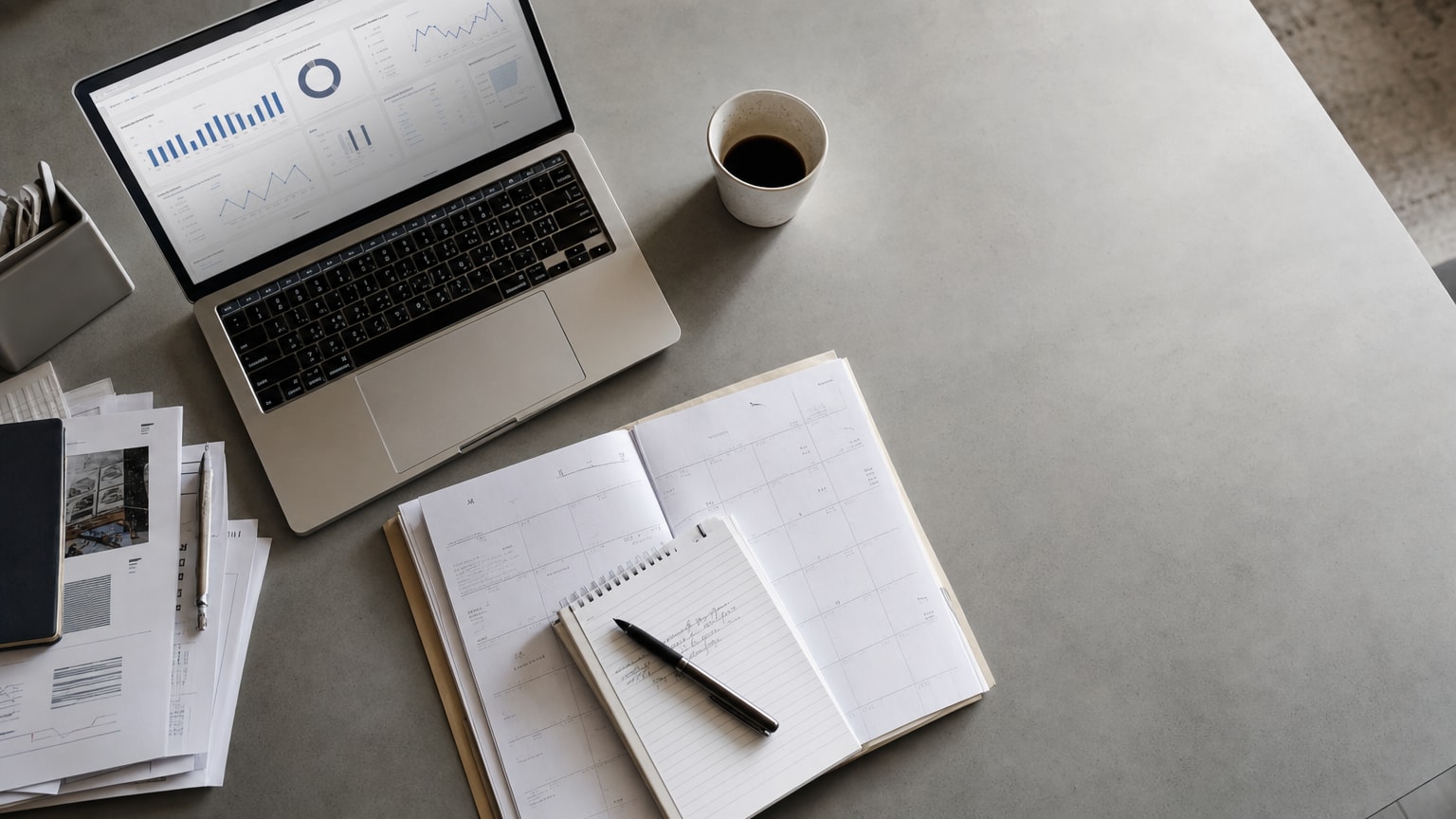 Ein aufgeräumter Schreibtisch mit einem Quartalskalender, einem Laptop mit Marketing-Dashboard und einer Tasse Kaffee — klare, fokussierte Arbeitsatmosphäre in einem kleinen Büro.