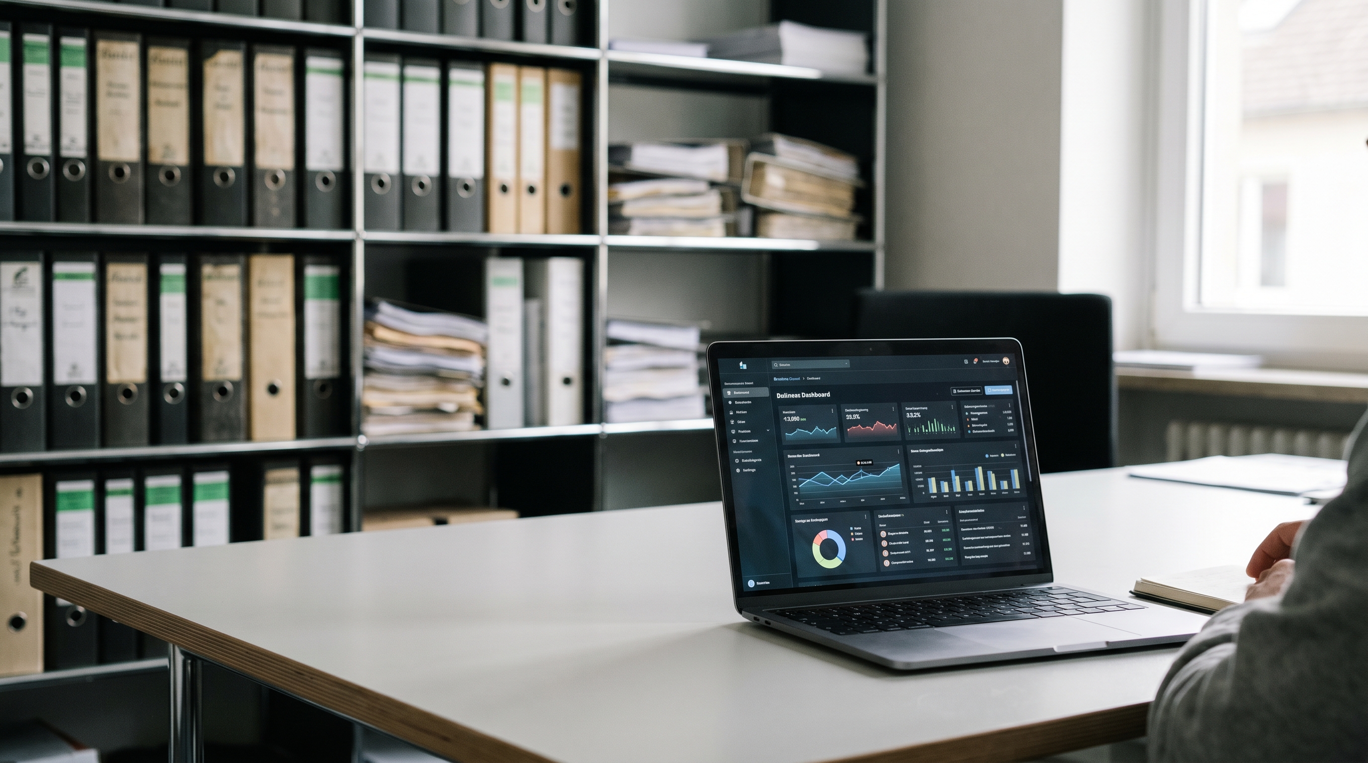 Modernes Büro mit aufgeräumtem Schreibtisch, auf dem ein Laptop mit einem digitalen Dashboard steht — im Hintergrund verschwommen ein Aktenordner-Regal, das Kontrast zwischen alter und neuer Arbeitswelt symbolisiert.