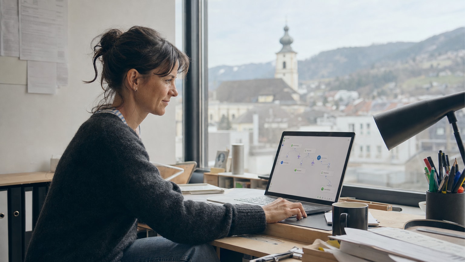 Ein kleiner Handwerksbetrieb mit aufgeräumtem Schreibtisch, auf dem ein Laptop steht. Auf dem Bildschirm sind einfache Automatisierungs-Workflows zu sehen. Helle, optimistische Atmosphäre, österreichische Kleinstadt im Hintergrund durch das Fenster sichtbar.