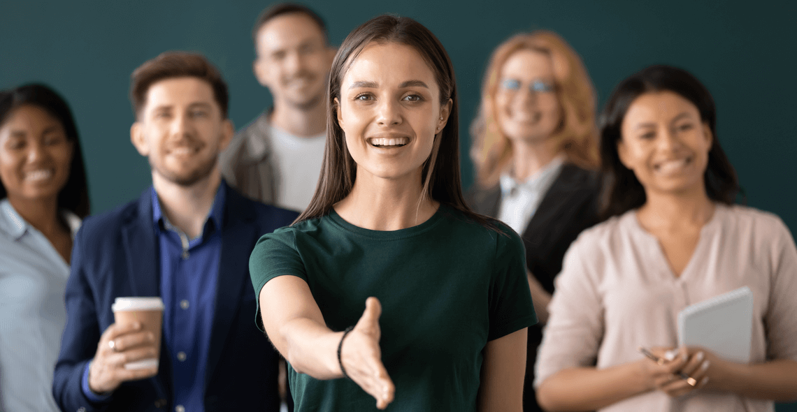 Smiling woman extending her hand to welcome a new team member during safer recruitment