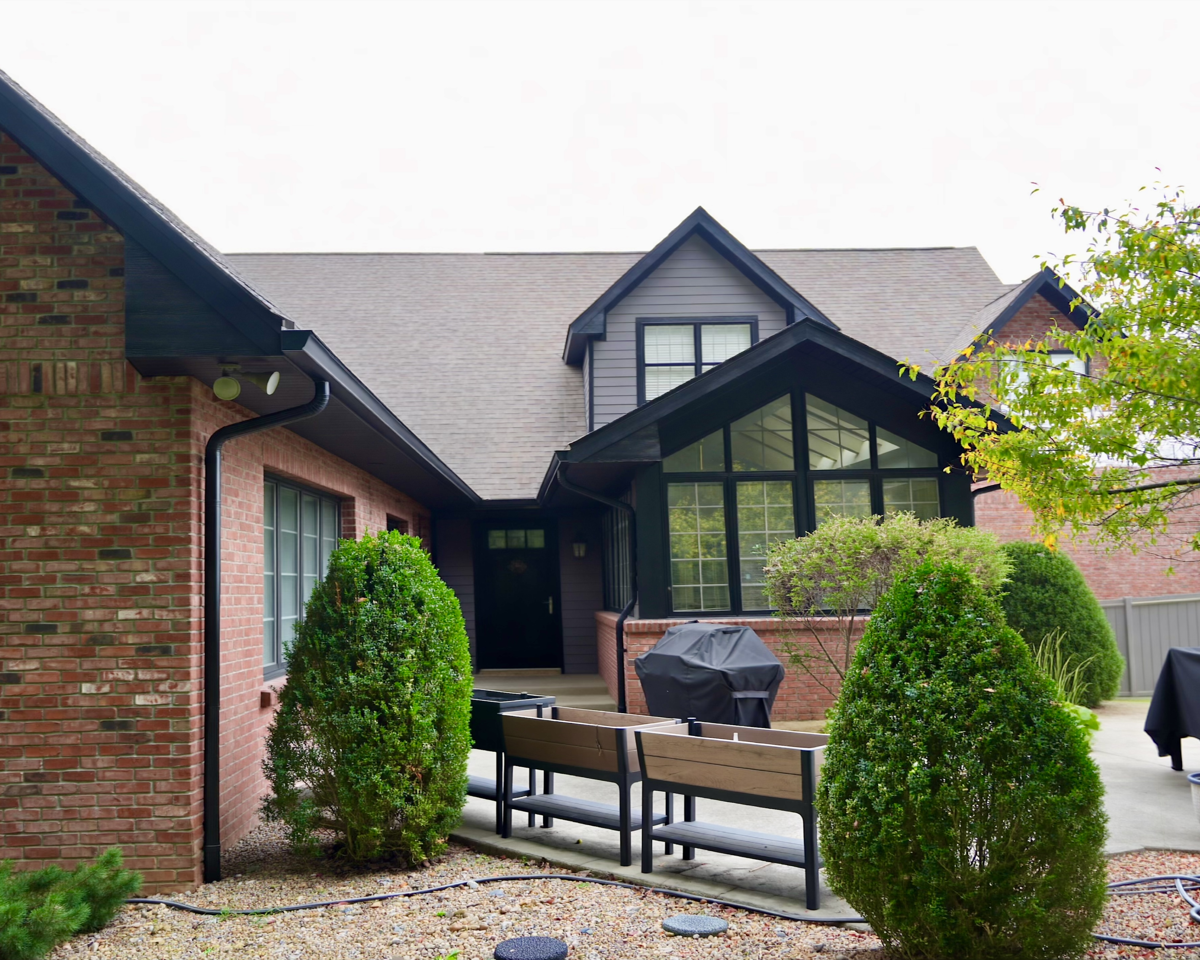 Transform your home exterior with an earthy modern paint palette. Learn how Sherwin Williams Urbane Bronze SW 7048 and Tricorn Black SW 6258 harmonize seamlessly with red brick and wooded landscapes. Discover professional painting tips on color theory, low LRV undertones, and faux stained porch columns for standout curb appeal. Read the full case study at https //craftsmanpainter.com/blog/how-sherwin-williams-urbane-bronze-sw-7048-and-tricorn-black-sw-6258-grounded-th