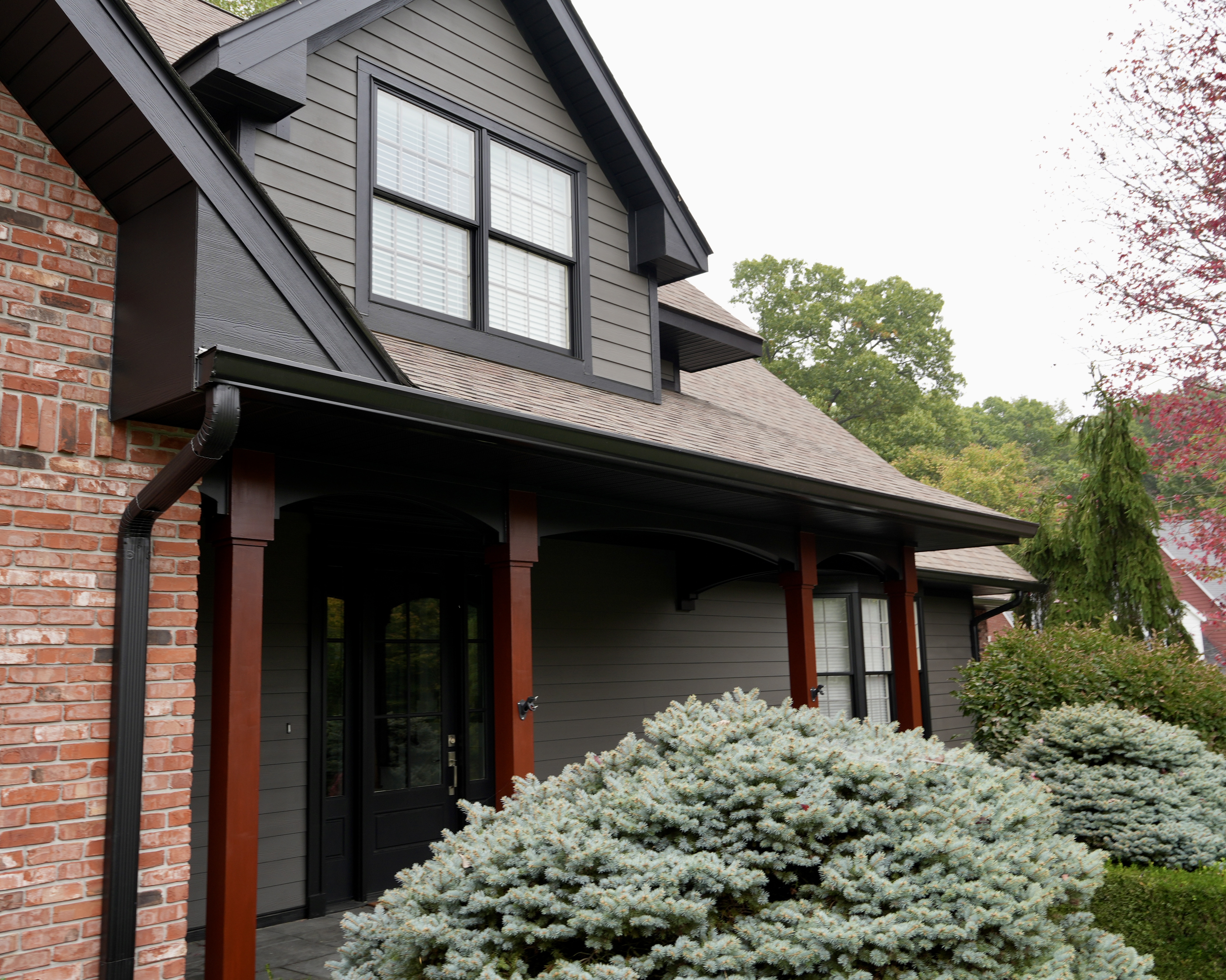 Transform your home exterior with an earthy modern paint palette. Learn how Sherwin Williams Urbane Bronze SW 7048 and Tricorn Black SW 6258 harmonize seamlessly with red brick and wooded landscapes. Discover professional painting tips on color theory, low LRV undertones, and faux stained porch columns for standout curb appeal. Read the full case study at https //craftsmanpainter.com/blog/how-sherwin-williams-urbane-bronze-sw-7048-and-tricorn-black-sw-6258-grounded-th