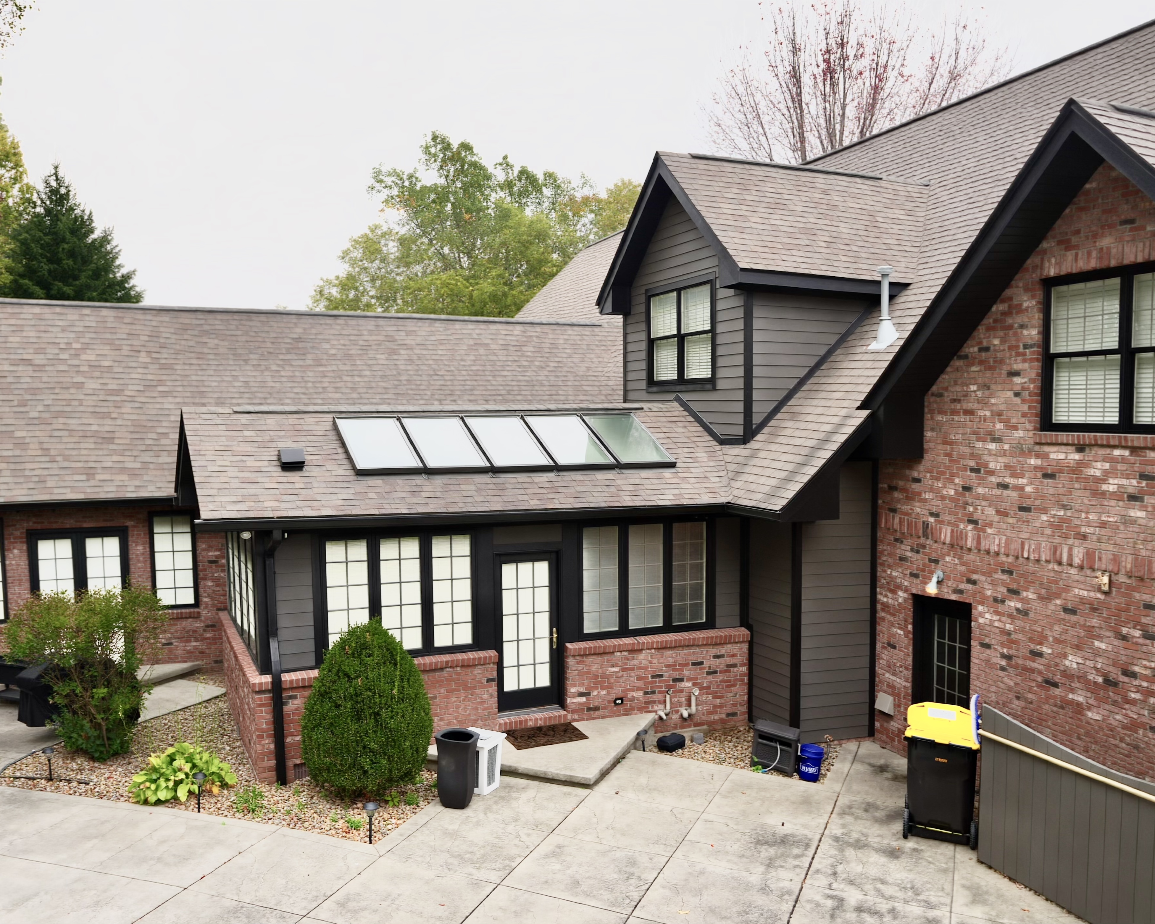 Transform your home exterior with an earthy modern paint palette. Learn how Sherwin Williams Urbane Bronze SW 7048 and Tricorn Black SW 6258 harmonize seamlessly with red brick and wooded landscapes. Discover professional painting tips on color theory, low LRV undertones, and faux stained porch columns for standout curb appeal. Read the full case study at https //craftsmanpainter.com/blog/how-sherwin-williams-urbane-bronze-sw-7048-and-tricorn-black-sw-6258-grounded-th
