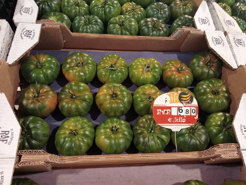 Boxes of green-shouldered RAF tomatoes with a euro-per-kilo price sign on a market stall in Almería