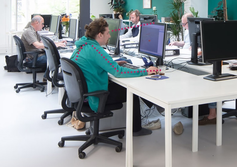 Számítógépes munkahely, vonalakkal jelölve a monitorra nézés iránya, valamint a hát, felkar és alkar vonala