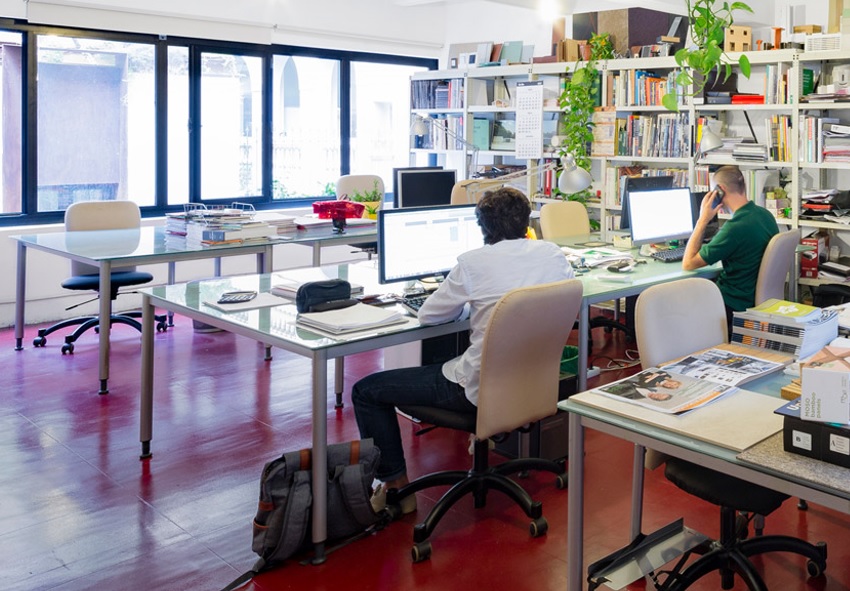 Iroda nagy ablakokkal, szemben asztalokkal.