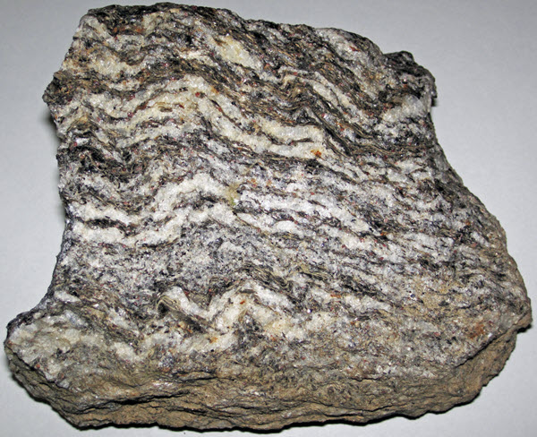 A hand sample of crystalline rock with distinct light and dark layers.