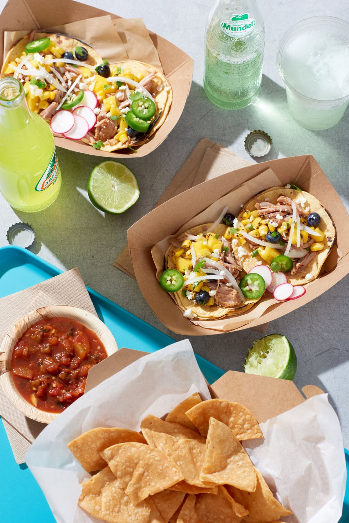 street tacos with chips and salsa and green sodas in glass bottles