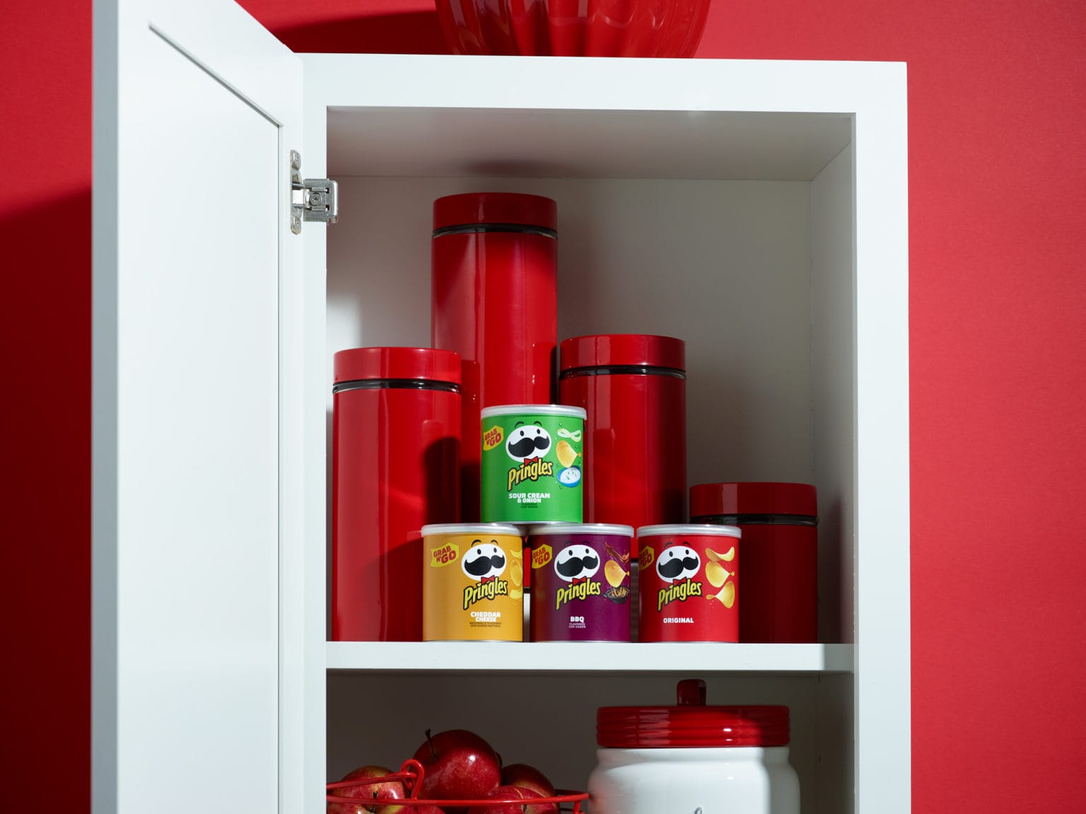 Pringles in cupboard with red containers 