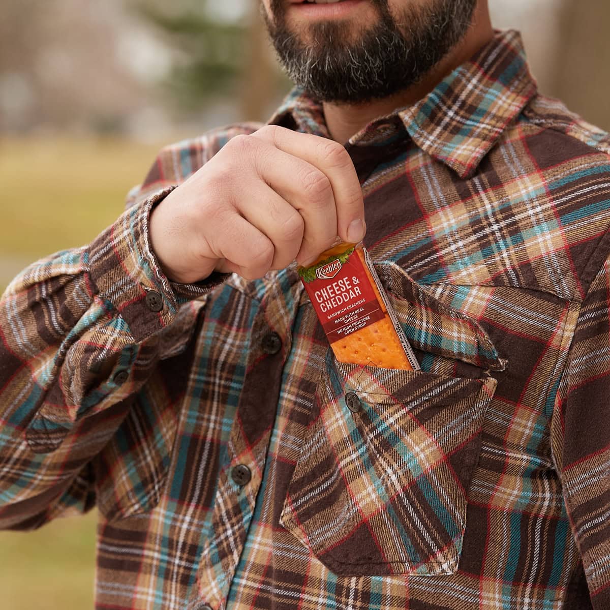 man outside pulling cheddar crackers package out of pocket