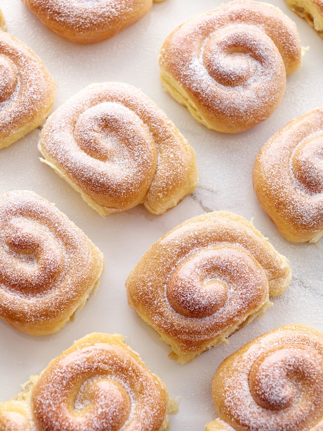 cinnamon rolls in a line pattern, sprinkled with powdered sugar. 