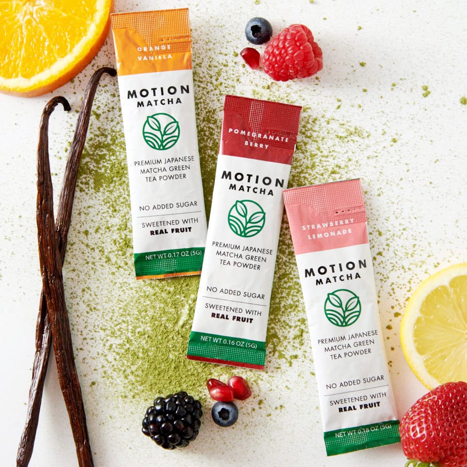 Motion matcha drink quick make packets on table with berries, fruit, and anise sticks. 