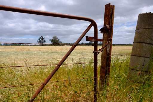 Rusted rural gate beside the O’Keefe Rail Trail near Axedale, photographed in 2016. Exact capture location unavailable. Photo: Damon Clarke, CC BY 3.0. Source: https://commons.wikimedia.org/wiki/File:Rusted_(192358249).jpeg · https://creativecommons.org/licenses/by/3.0