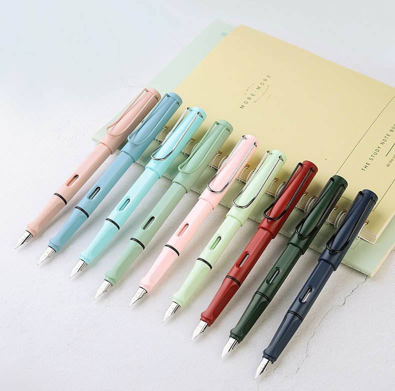 Nine pastel and dark fountain pens arranged beside notebooks