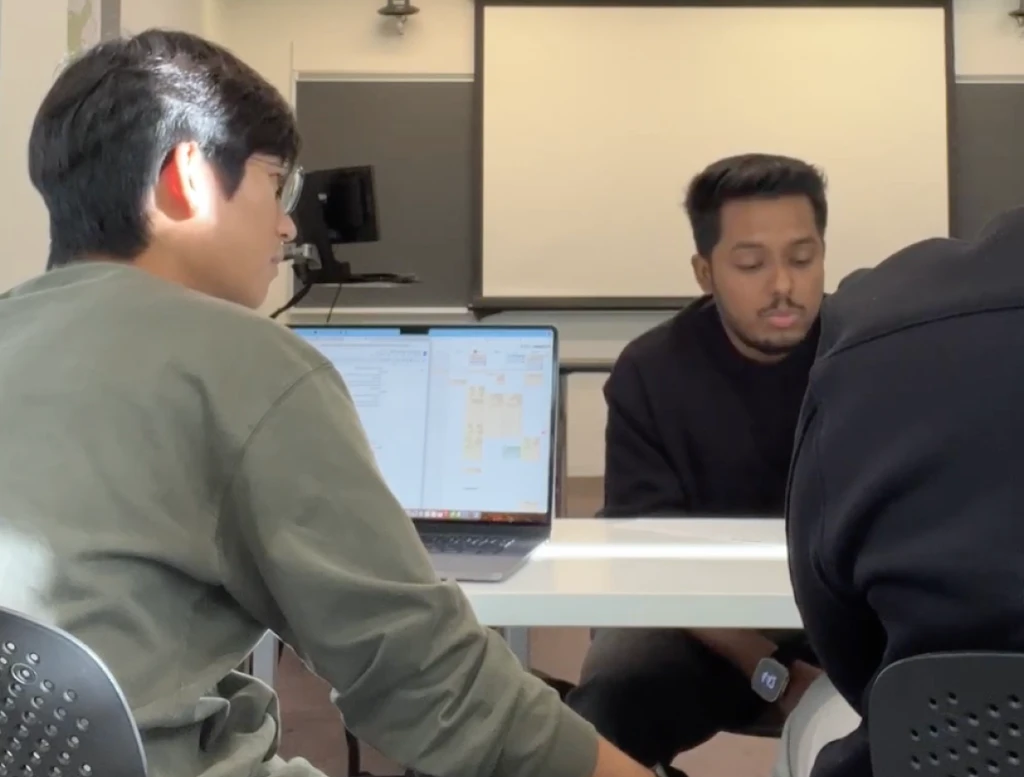Chayan's interview: a researcher across the table reviewing notes on a laptop