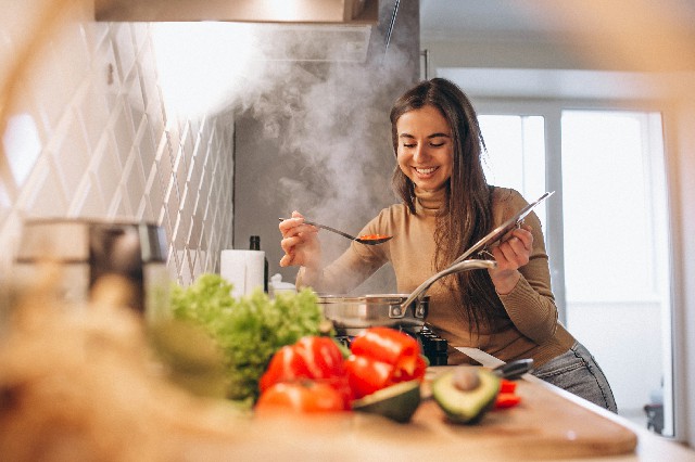 Cocinera feliz preparando un plato en su cocina